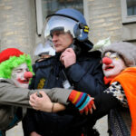 Climate change demonstrators dressed as clowns hug a police officer outside the Danish Foreign Ministry while demonstrators pass during the climate march in Copenhagen on December 12, 2009. At least 30,000 people marched through Copenhagen, demanding world leaders declare war on the greenhouse gases that threaten future generations with hunger, poverty and homelessness. If all goes well, the 194-nation conference under the UN's Framework Convention on Climate Change (UNFCCC) will wrap up on December 18 with a historic deal sealed by more than 110 heads of state and government. TOPSHOTS/ AFP PHOTO/ ADRIAN DENNIS (Photo credit should read ADRIAN DENNIS/ AFP/ Getty Images)